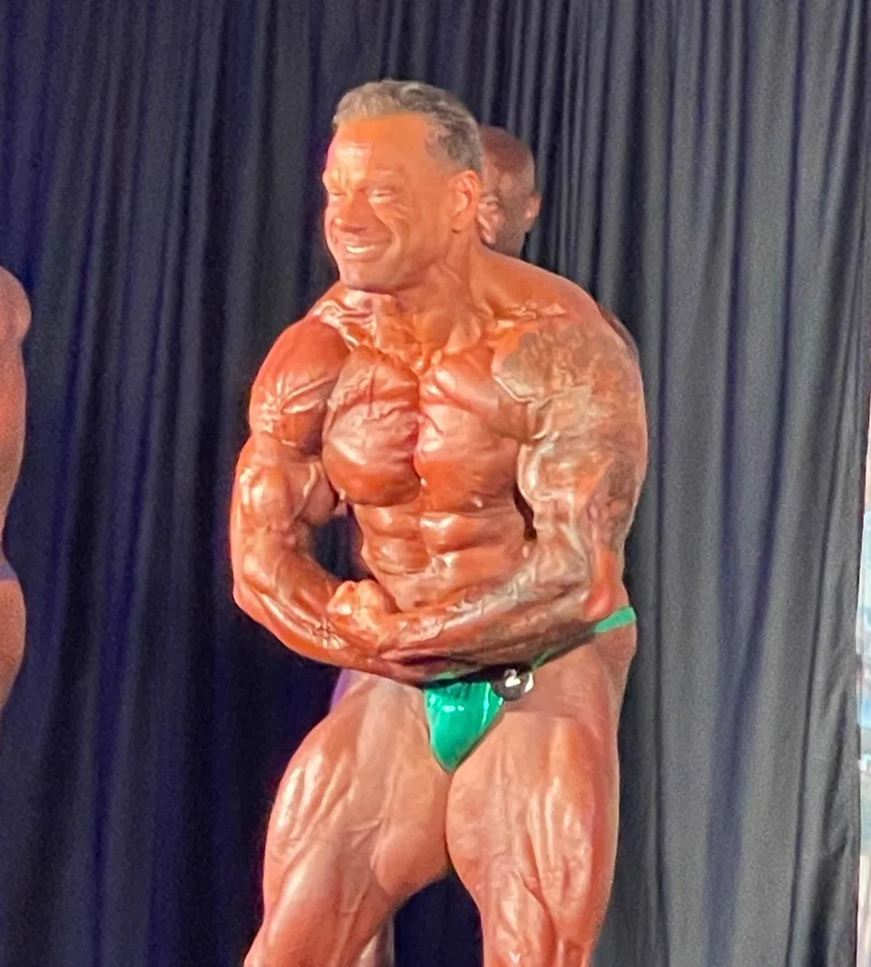 A Cardone Nutrition client competing on stage at a bodybuilding show.
