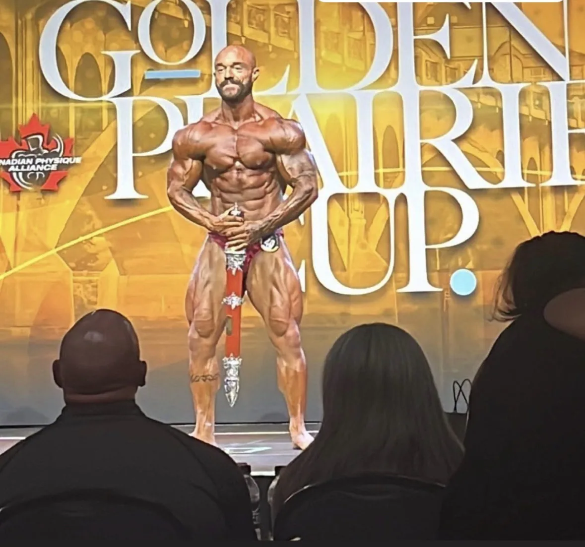 A Cardone Nutrition client competing on stage at a bodybuilding show.