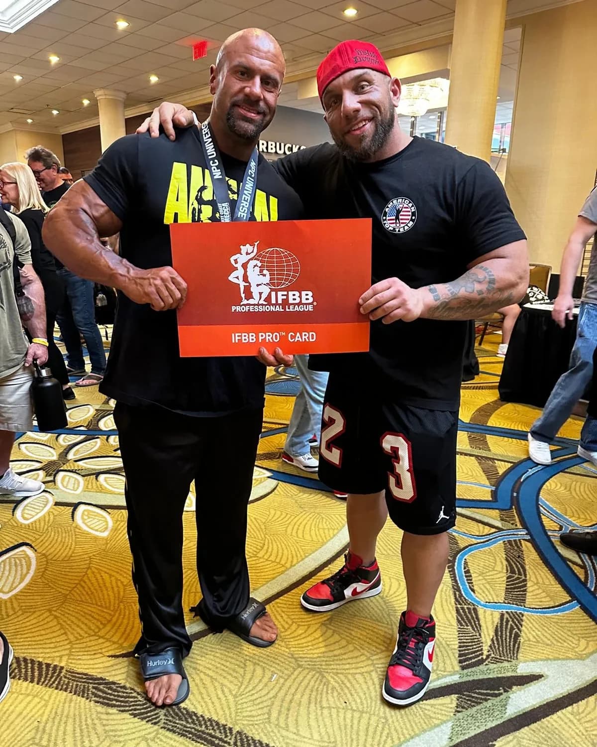 Dom Cardone standing with a coaching client who is holding a newly earned IFBB pro card.